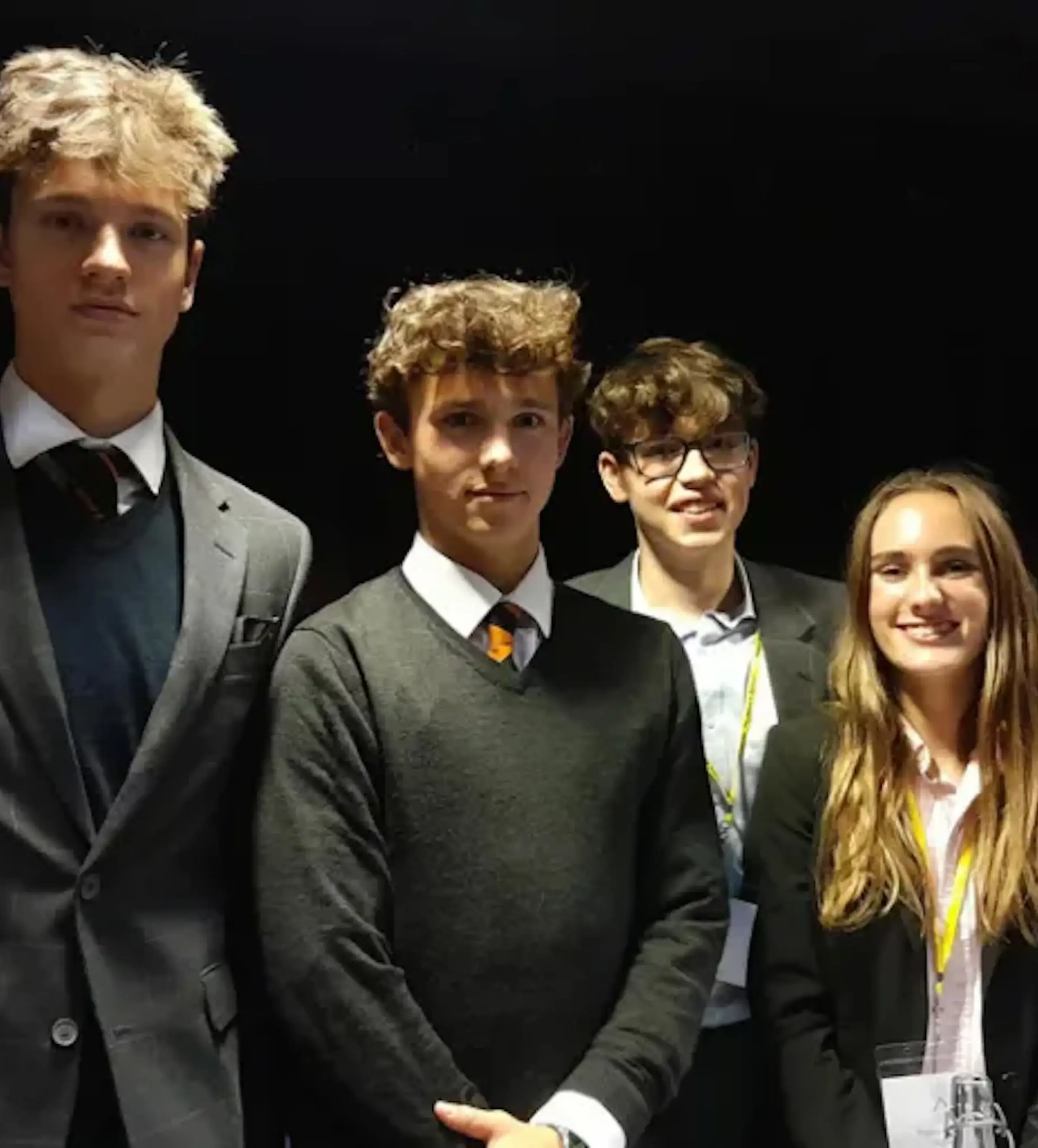 Four students pose against a black backdrop